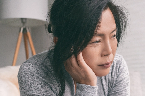 Adrenal-Fatigue-Doctor A middle-aged asian woman sitting on her couch, resting her head on her hand, suffering from adrenal fatigue. Get treatment for adrenal fatigue syndrome from Frank Lanzisera, D.C. in Tampa Bay Metro.