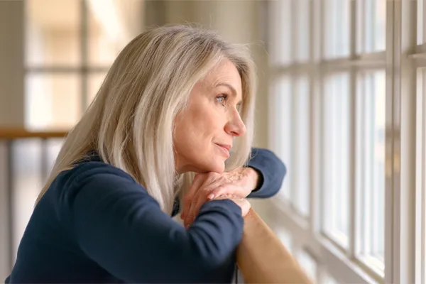 Adrenal-Hormone-Disorder-Clinic A mature woman in a blue shirt looks out the window with melancholy. Schedule treatment for adrenal hormone disorder from Frank Lanzisera, D.C. in Tampa Bay Metro.