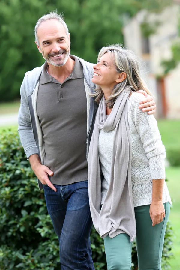Bioidentical-Hormone-Therapy-Treatment A mature couple in gray toned clothes and jeans walk happily outside, happy with their successful bioidentical hormone treatments from Frank Lanzisera, D.C. in Tampa Bay Metro.