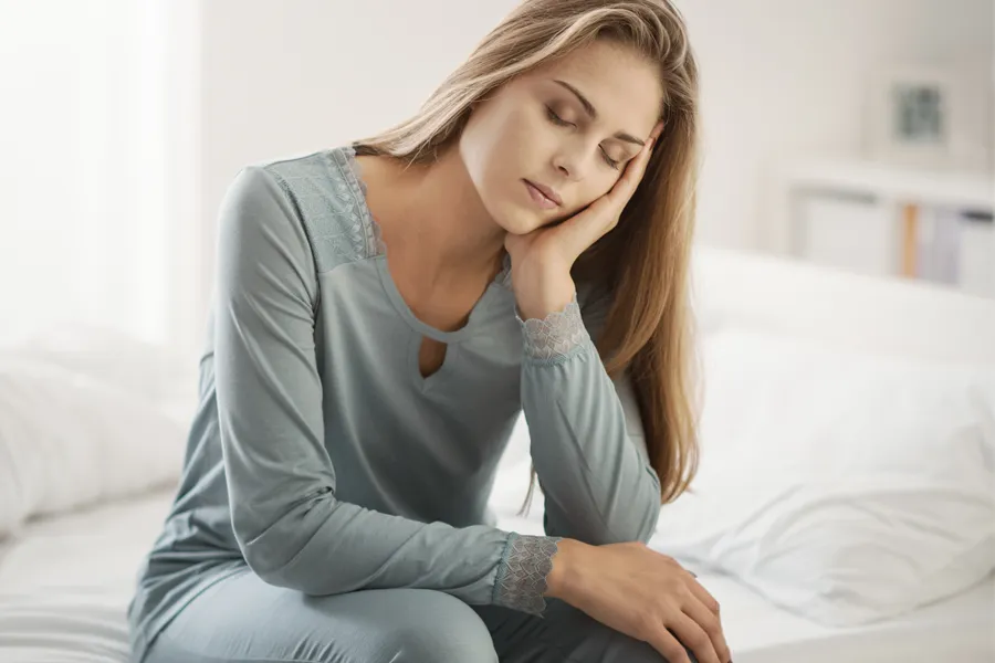 Depression-Clinic A woman sits on the edge of her bed with her head in her hands. Schedule treatment for depression from Frank Lanzisera, D.C. in Tampa Bay Metro.