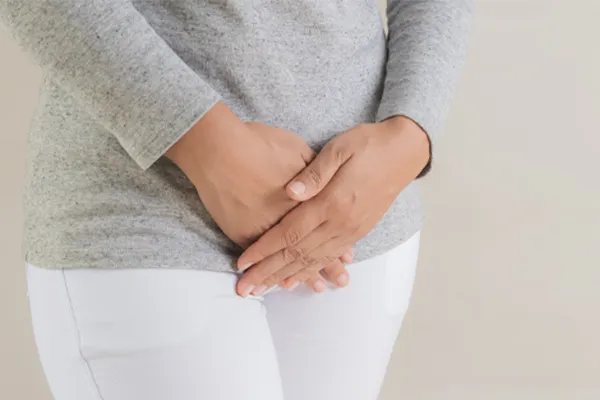 Fibroids-Clinic Close up of a woman in a gray shirt and white pants holding her hands below her abdomen in discomfort. Get treatment for fibroids from Frank Lanzisera, D.C. in Tampa Bay Metro.