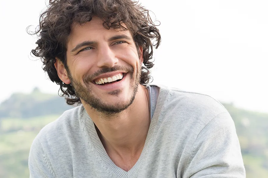 Hair-Loss-Clinic A man with radiant curly hair and a confident smile looks to the horizon. Frank Lanzisera, D.C. in Tampa Bay Metro offers effective therapies to support hair regrowth and scalp health to treat hair loss.