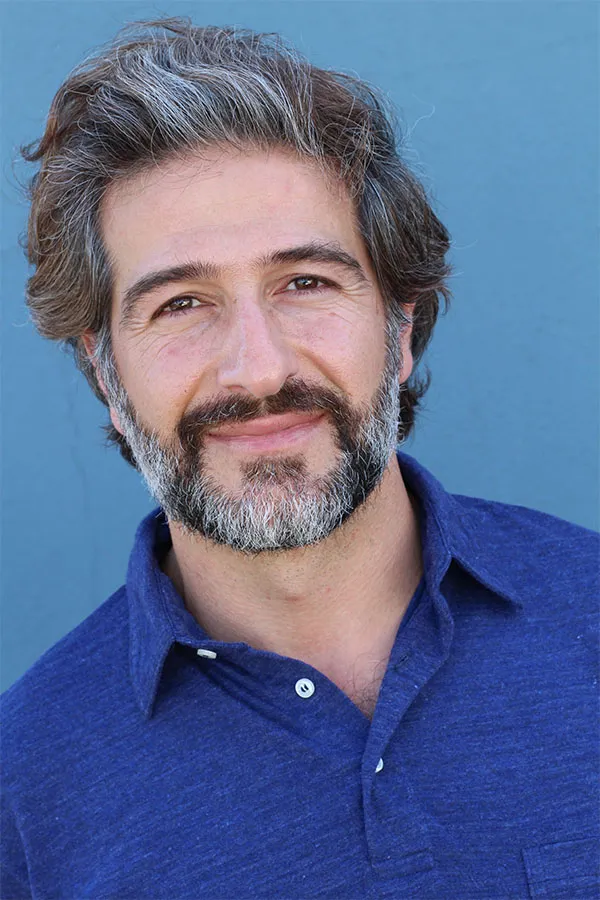 Hair-Loss-Treatment Image of a cheerful man with a bright smile and curly hair against a natural landscape. Frank Lanzisera, D.C. provides personalized hair loss treatments in Tampa Bay Metro.