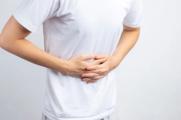 Irritable-Bowel-Syndrome-Clinic A person holding their stomach in visible discomfort against a plain background. Frank Lanzisera, D.C. treats irritable bowel syndrome with functional medicine in Tampa Bay Metro.