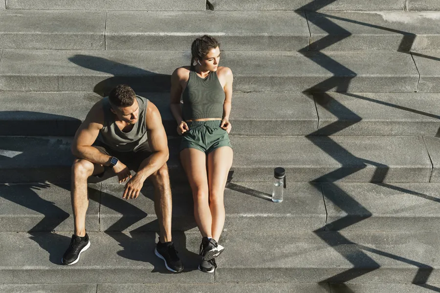 Medical-Weight-Loss-Doctor A couple in gray and green track clothes resting after a workout on stone steps, happy with their weight loss plans from Frank Lanzisera, D.C. in Tampa Bay Metro.