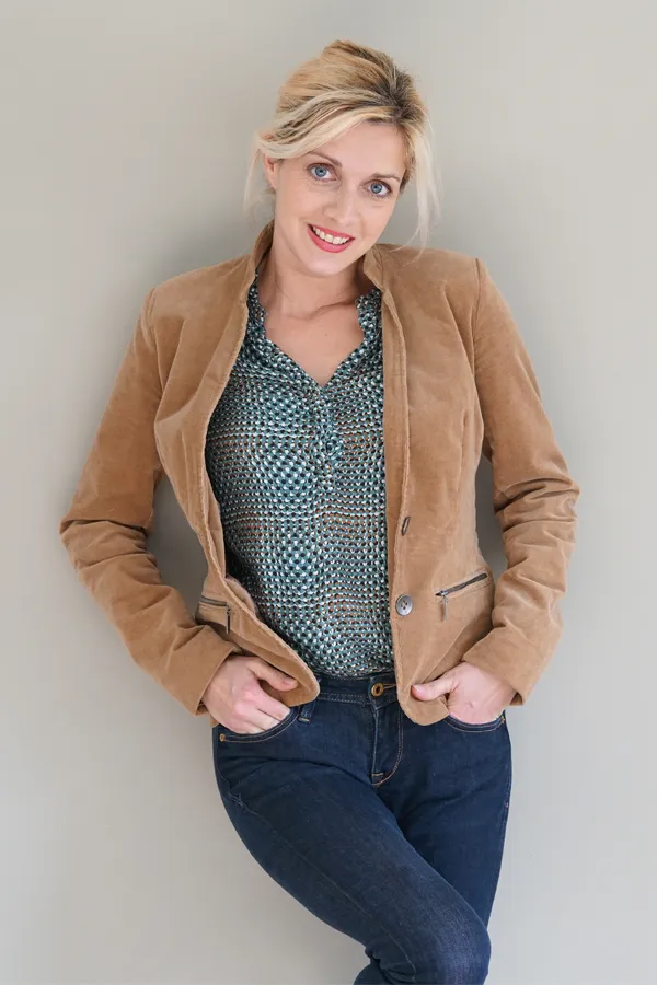 Metabolic-Syndrome-Treatment A smiling blonde woman in a tan leather jacket leans against a gray wall. Schedule metabolic syndrome from Frank Lanzisera, D.C. in Tampa Bay Metro.
