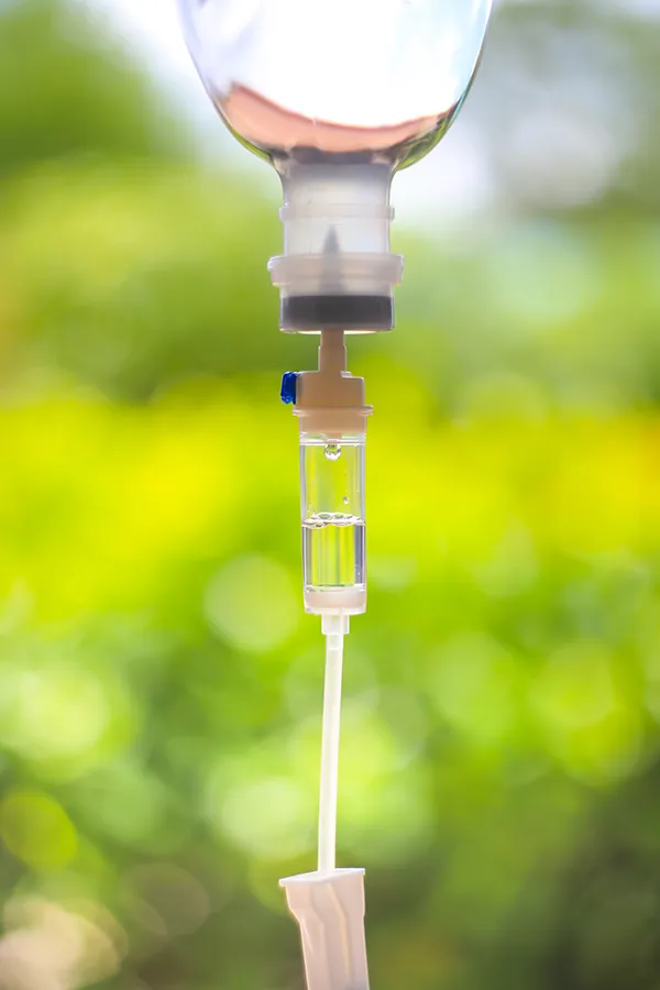 Myers-Cocktail-Treatment Close-up of an IV drip against a forest background. Get the Myers Cocktail IV treatment from Frank Lanzisera, D.C. in Tampa Bay Metro.