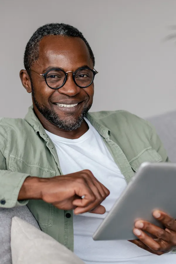 Neurofeedback-Therapy-Treatment A smiling Black man working on a tablet. Get neurofeedback therapy from Frank Lanzisera, D.C. in Tampa Bay Metro.