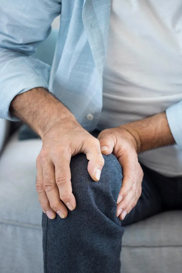 Osteoporosis-Pain A close-up of a man holding his knee while experiencing pain from osteoporosis. Get osteoporosis treatment from Frank Lanzisera, D.C. in Tampa Bay Metro.