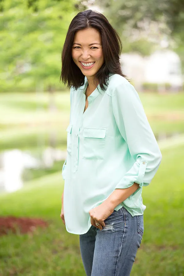 Perimenopause-Treatment A middle-aged brunette woman in a light green button-up shirt stands outside smiling, happy with her perimenopause treatment from Frank Lanzisera, D.C. in Tampa Bay Metro.