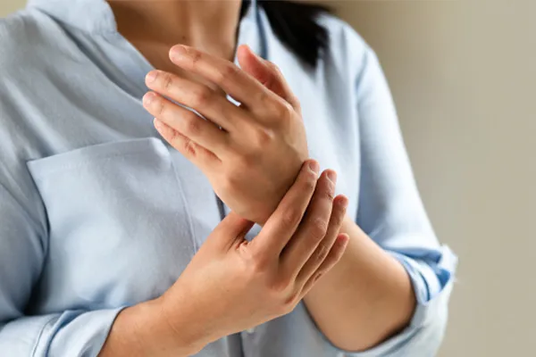 Rheumatoid-Arthritis-Clinic Close up of a woman in a blue blouse rubbing her wrist. Get rheumatoid arthritis treatment from Frank Lanzisera, D.C. in Tampa Bay Metro.