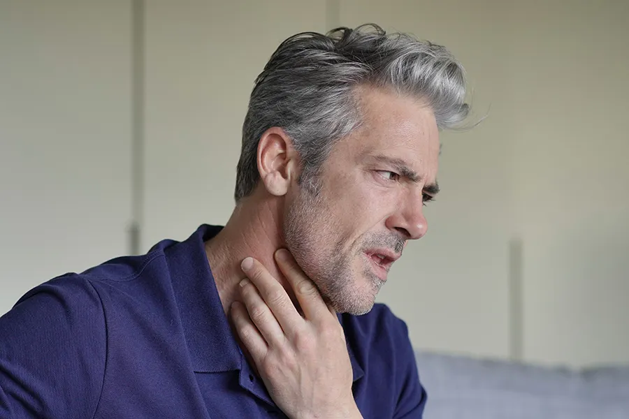 Thyroid-Symptoms-Clinic A man touches his throat with concern. Get treatment for thyroid symptoms from Frank Lanzisera, D.C. in Tampa Bay Metro.